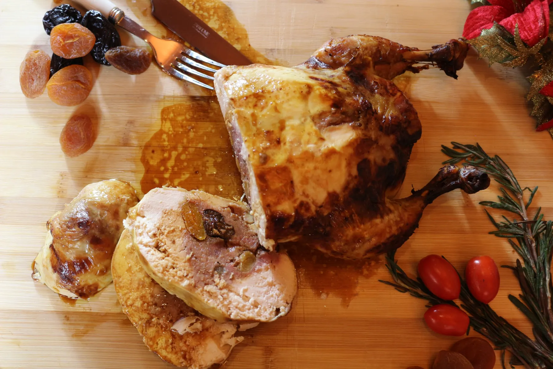 Pularda rellena cortada sobre una tabla, con la mesa puesta al fondo